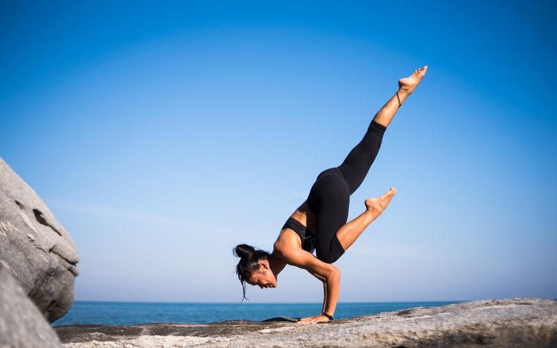 Persona realizando postura de yoga al amanecer junto a una ventana